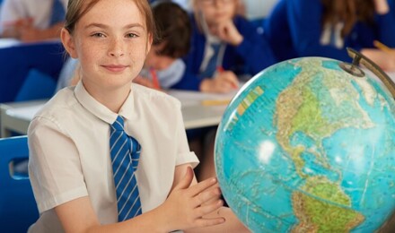 Child looking to camera whilst touching a globe