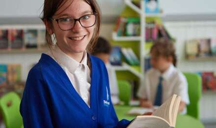 Child looking to camera whilst holding a book