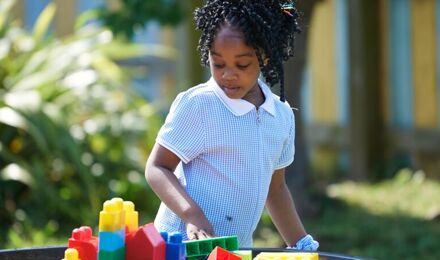 Child looking at colourful blocks outside nursery
